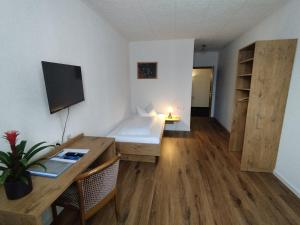 新乌尔姆索耐科勒酒店的小房间设有书桌和一张桌子及一台电脑
