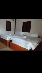 Ban OKonglor Khamchalern Guesthouse and Restaurant的配有白色床单的客房内的两张床