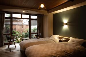 丰冈市城崎温泉 旅館 つばき乃 - Kinosaki Onsen Ryokan Tsubakino的酒店客房设有两张床和窗户。