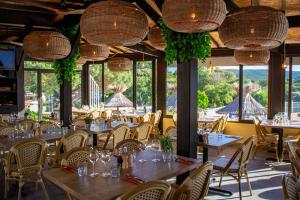 加桑Bungalow luxe 3 chambres surplombant le Golf de St Tropez的餐厅设有桌椅和大窗户。