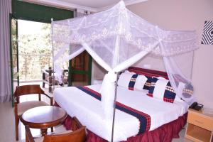 KaragariKingfisher Resort-Muhazi的一间卧室配有一张带桌椅的天蓬床