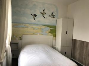 滨海卡约Logis - Le Neptune Hôtel & Restaurant的卧室配有白色的床,墙上有鸟儿