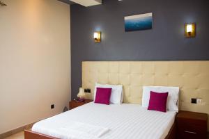 科托努IMOLEASE Kouessi Menontin的卧室配有一张大床和两个粉红色枕头