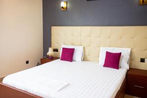 科托努IMOLEASE Kouessi Menontin的卧室配有一张带紫色枕头的大型白色床。