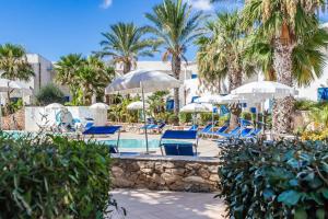 法维尼亚纳Resort Cala La Luna的一个带蓝色椅子和遮阳伞的游泳池,并种植了棕榈树