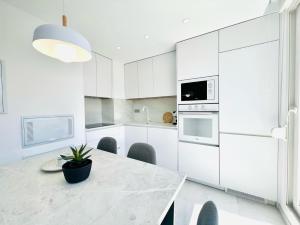 托雷维耶哈Sunrise Center Suites的厨房配有白色橱柜和盆栽桌子
