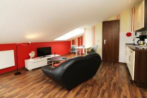 卡尔斯哈根QUARTIER 18 - Studio Sonnenschein 2 strandnah的客厅配有黑色真皮沙发和红色墙壁