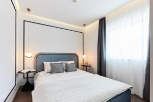 布达佩斯The Amberlyn Suite Hotel的卧室配有白色的床和大窗户
