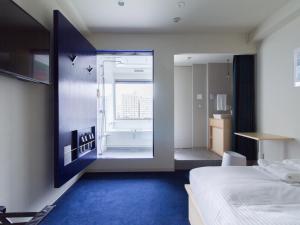 东京东京清澄LYURO酒店-共享酒店(The Share Hotels Lyuro Tokyo Kiyosumi) 的一间卧室配有一张床,浴室设有浴缸