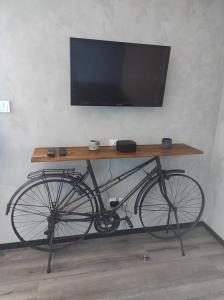 马洛塞讷Apparts'hôtel la ferme du gros noyer的坐在桌子下,放着电视的自行车