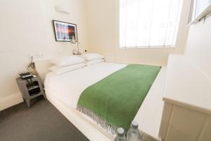 都柏林凯利酒店的卧室配有一张带绿毯的白色床