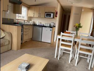 佩恩顿Gorgeous 3 bed static caravan at Hoburne Devon Bay, pet friendly的厨房以及带桌椅的起居室。