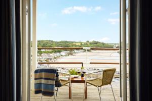 桑德斯富特St Brides Spa Hotel & Village Apartments的阳台配有桌椅,享有海港的景致。