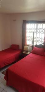 蒙特哥贝Melrose Place的一间卧室设有两张红色的床和窗户