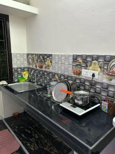 根尼亚古马里Tamizh Nest - தமிழ்க்குடில்的厨房柜台配有炉灶上的锅碗瓢盆