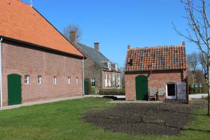 阿赫特克克Trekkershuisje 't Zeeuws Knoopje的一座古老的砖砌建筑,设有绿门和谷仓