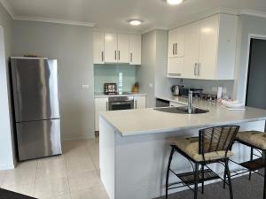 新普利茅斯Seaside Wanaka Tce的厨房配有白色橱柜、水槽和冰箱。