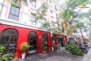 下龙湾Bài Thơ Mountain Hotel的一条树木和植物林立的街道上的红色建筑