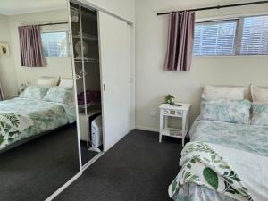 芒阿法埃Mangawhai Modern的一间卧室配有两张床和镜子