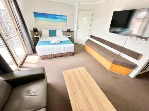纳鲁马陶坡唐汽车旅馆的一间卧室配有一张床、一台电视和一张沙发
