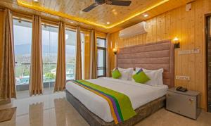达兰萨拉Treebo Trend Ortus Residency的一间卧室设有一张大床和大窗户