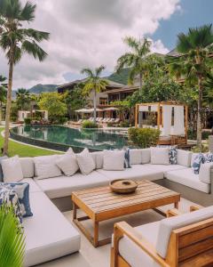马埃岛L'Escale Resort Marina & Spa - Small Luxury Hotels of the World的一个带沙发和桌子的庭院和一个游泳池