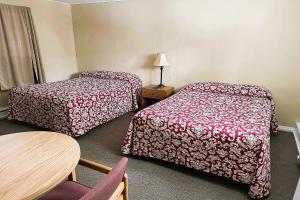 艾恩伍德Love Hotels Timberline at Lake Superior MI的酒店客房设有两张床和一张桌子。