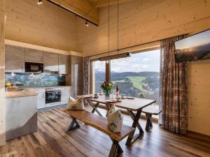 伊特尔Alpenchalets Oberlaiming的厨房以及带桌子和大窗户的用餐室。