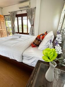 Ban Yang PlaoSoft Resort Kad Farang Hangdong的一间卧室配有一张床和一张花瓶桌子