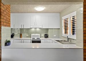 萨维特尔Driftwood Court 1的白色的厨房配有白色橱柜和水槽