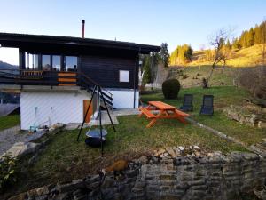 施瓦尔茨湖Ferienwohnung im Chalet am Bach的院子里带野餐桌和椅子的房子