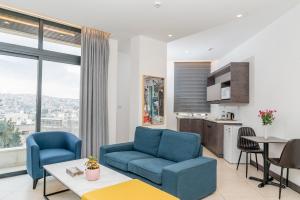 安曼Liv Weibdeh Hotel Suites的一间带2把蓝色椅子的客厅和一间厨房