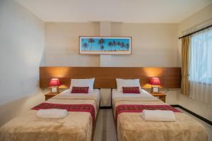 库塔Kuta Suci Guesthouse的配有2盏灯的酒店客房的2张床