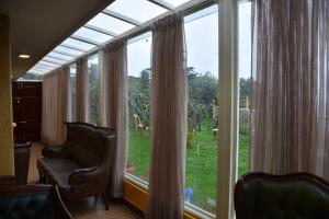 乌提Glen Premium Villa By LexStays的一间房间,前方设有大窗户和椅子