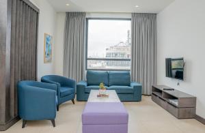 安曼Liv Weibdeh Hotel Suites的客厅配有2把蓝色椅子和电视