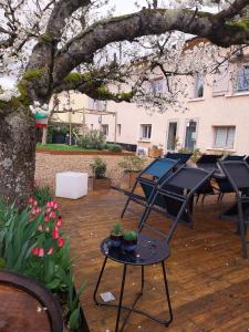 CharentayLa Maison des Vignes的庭院里设有桌子和一棵树,种有鲜花