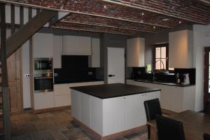 蒂尔特De Landweg的厨房配有白色橱柜和黑色台面