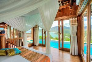 小通奈潘Santhiya Koh Phangan Resort and Spa的一间卧室设有一张床,享有游泳池的景色