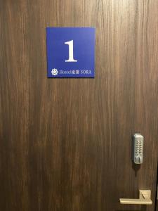 京都Higashi Shimbashi Building 3F Hostel Gion SORA - Vacation STAY 92728v的木门,上面有标志,有电话