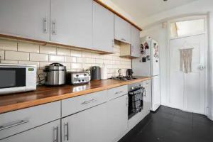 伦敦Alross Room with Breakfast的厨房配有白色橱柜和木制台面