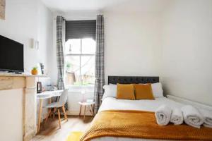 伦敦Alross Room with Breakfast的一间卧室配有一张床、一张书桌和一个窗户。