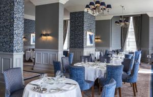 伊斯特布恩格兰德大酒店的餐厅设有白色的桌子和蓝色的椅子