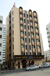 沙迦DANA HOTEL的一座大型建筑,前面有汽车停放