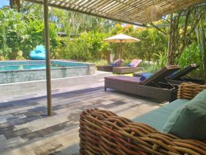 塞隆贝拉纳克Villa Jeruk的一个带椅子和遮阳伞的庭院和一个游泳池