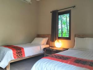 塞隆贝拉纳克Villa Jeruk的一间卧室设有两张床和彩色玻璃窗。
