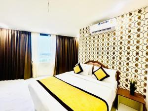 商沙巴HOTEL EAGLE GRAND的酒店客房配有一张带黄白色毯子的床。