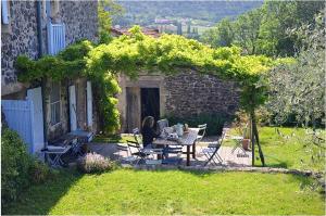 Saint-Lager-BressacMaison de 5 chambres avec piscine privee jardin clos et wifi a Saint Lager Bressac的坐在花园桌子上的女人