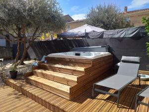 Villes-sur-AuzonDeux M的木甲板上的热水浴池,配有椅子