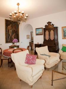 伊斯基亚Appartamento in villa vista mare的客厅配有白色椅子和吊灯。
