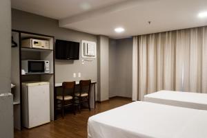 阿雷格里港Master Express Cidade Baixa - Próximo à UFRGS e à Santa Casa的酒店客房设有两张床、一台微波炉和一间厨房。